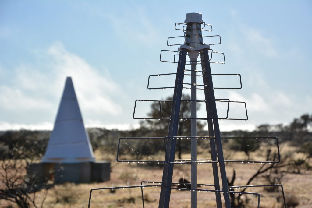 An SKA-Low test antenna in the foreground of the BIGHORNS Epoch of Reionisation experiment, both at the Murchison Radio-astronomy Observatory.
