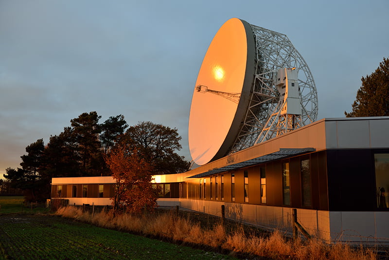 The SKA Organisation Headquarters, at Jodrell Bank Observatory near Manchester, UK, and the Lovell Telescope in the background. Credit: SKA, R. Millenaar (ASTRON/SKA).
