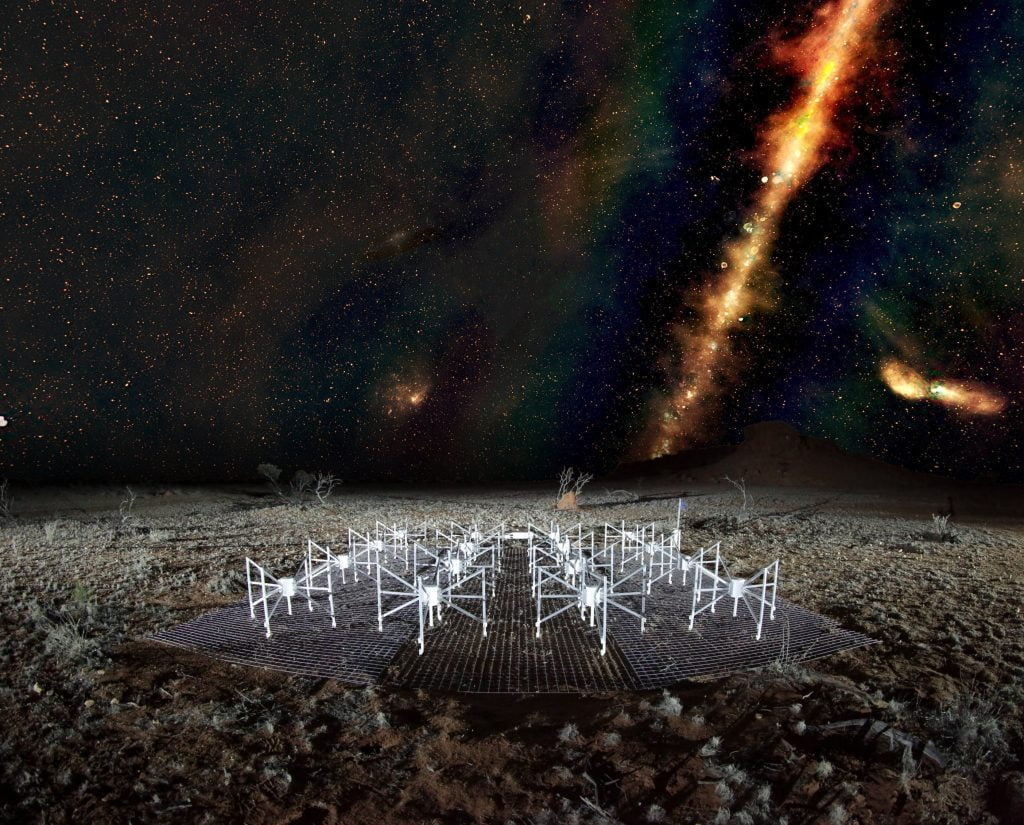 A ‘radio colour’ view of the sky above a ‘tile’ of the Murchison Widefield Array radio telescope, located in outback Western Australia. The Milky Way is visible as a band across the sky and the dots beyond are some of the 300,000 galaxies observed by the telescope for the GLEAM survey. Red indicates the lowest frequencies, green the middle frequencies and blue the highest frequencies. Credit: Radio image by Natasha Hurley-Walker (ICRAR/Curtin) and the GLEAM Team. MWA tile and landscape by Dr John Goldsmith / Celestial Visions.
