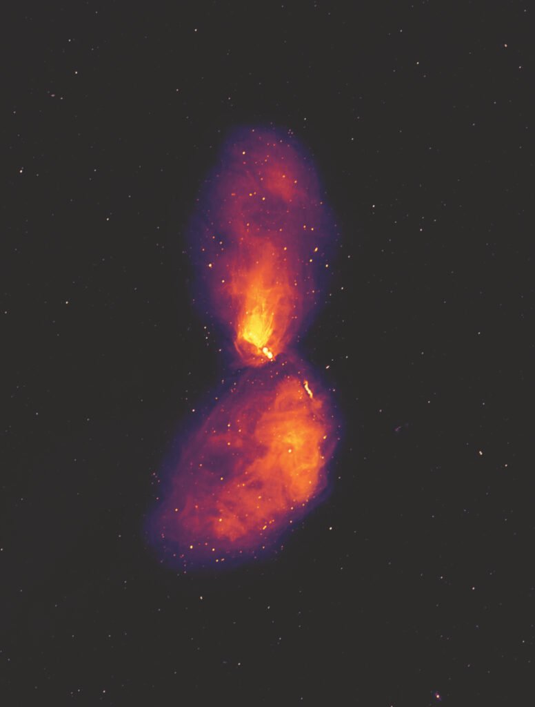Centaurus A is a giant elliptical active galaxy 12 million light-years away. At its heart lies a black hole with a mass of 55 million suns. This image shows the galaxy at radio wavelengths, revealing vast lobes of plasma that reach far beyond the visible galaxy, which occupies only a small patch at the centre of the image. The dots in the background are not stars, but radio galaxies much like Centaurus A, at far greater distances. Credits: Ben McKinley, ICRAR/Curtin and Connor Matherne, Louisiana State University