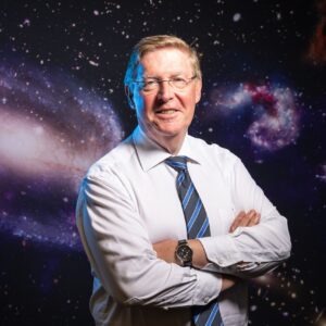 Professor Peter Quinn in 2019, against a backdrop of swirling galaxies.