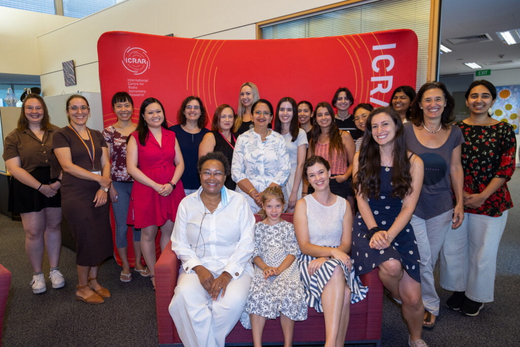 Group photo of ~20 women in front of a red ICRAR banner