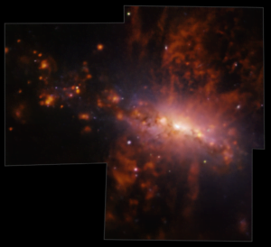 A blue-tinged spiral galaxy is seen edge on in the centre, with streams of orange-red gas streaming from the top and bottom.