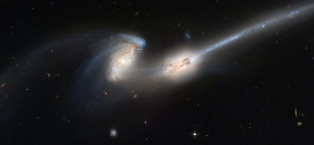 Two galaxies interacting, leaving a trail of stars behind them.
