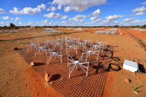 A square of bow-tie shaped radio antennas on top of the red soil of the WA outback